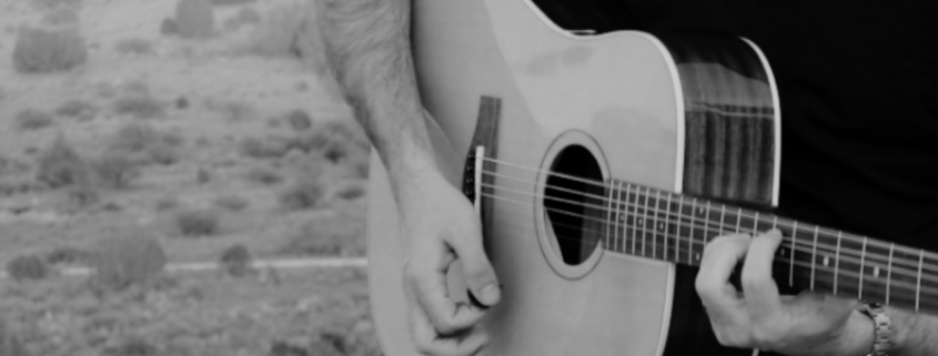 Musician playing a travel folding acoustic guitar outdoors, showcasing lightweight design and portability.