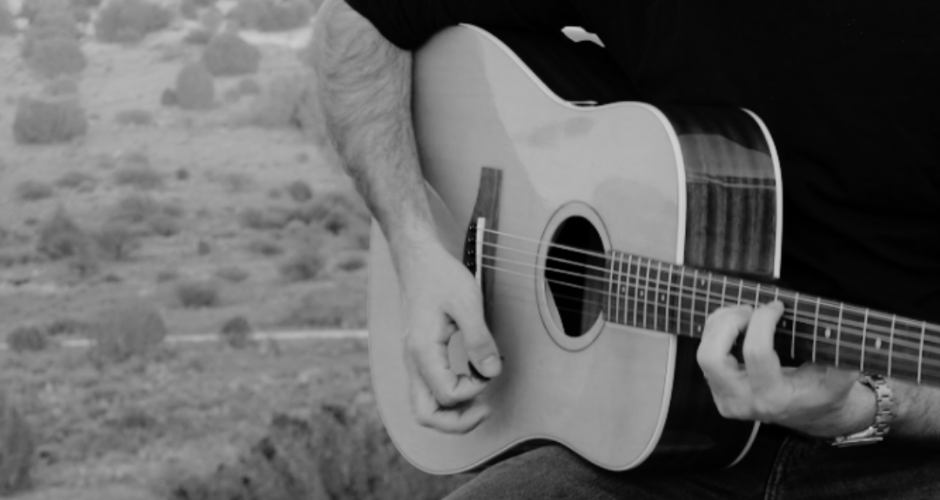Musician playing a travel folding acoustic guitar outdoors, showcasing lightweight design and portability.