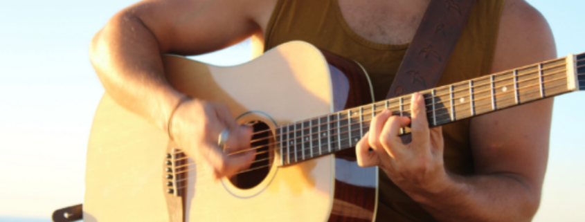 Musician playing a Voyage Air travel guitar outdoors, highlighting the lightweight, portable design ideal for on-the-go performance.